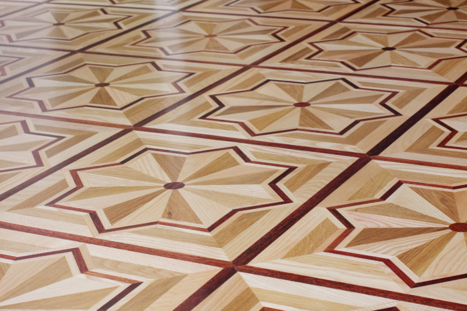 Decorative Neo Deco wood flooring featuring geometric starburst patterns, contrasting wood tones, and intricate inlay borders